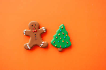 Festive Christmas concept background. Gingerbread man, fir tree cookies on an orange backdrop. Top...