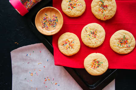 Shortbread cookies with confetti on a red napkin on a black stone background. Top view.の写真素材