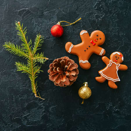 Christmas background. Gingerbread man and girl cookies, fir tree, balls on a black stone background. Top view. Square image.の写真素材