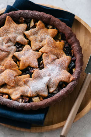 Chocolate gingerbread crust mince pie with vanilla stars on a white stone backgroundの写真素材
