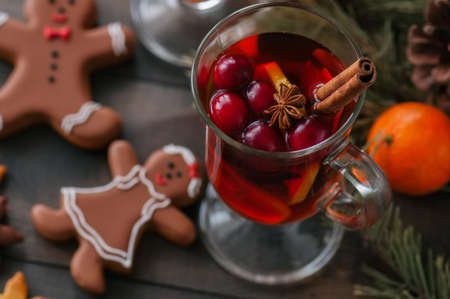 Mulled wine. Christmas hot drink with citrus, apple and spices in a glass cup and gingerbread cookies on a black background.の写真素材