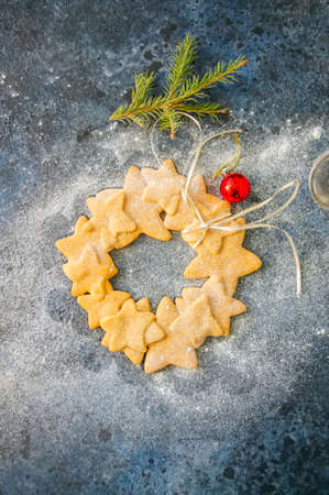 Gingerbread star cookies wreath with white ribbon sprinkled with powdered sugar, fir tree branch and...