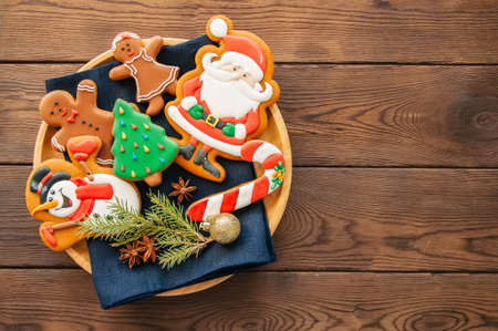 Plate with homemade glazed different shapes of christmas cookies. Top view and wooden backdrop.の写真素材