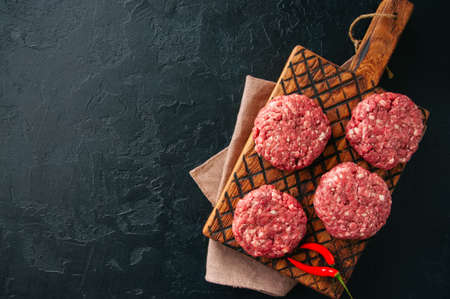 Raw ground meat beef burgers on a wooden board. の写真素材