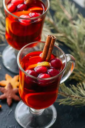 Mulled wine. Christmas hot drink with citrus, apple and spices in a glass cup on a black background.の写真素材