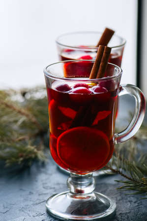 Mulled wine. Christmas hot drink with citrus, apple and spices in a glass cup on a black background.の写真素材