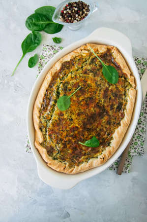 Quiche with spinach and cheese - savoty tart from flaky dough on a white stone backround with copy space.の写真素材