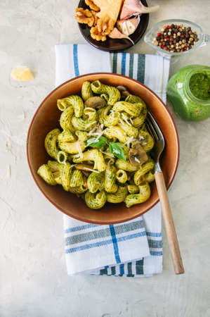 Cavatappi pasta with basil pesto and herbs in a plate on a white stone background.の写真素材