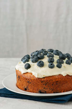 Sour cream and blueberry cake served on a plate on a white stone backgroundの写真素材