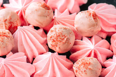 White chocolate and strawberry truffles and pink meringue kisses on black stone backgroundの写真素材