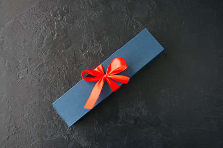 Blue gift box with red tape with chocolate on a black stone backgroundの写真素材