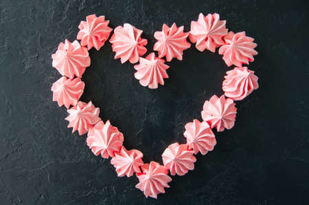 Pink meringue kisses on black stone background