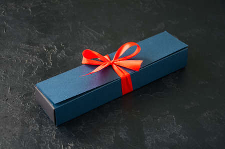 Blue gift box with red tape with chocolate on a black stone backgroundの写真素材