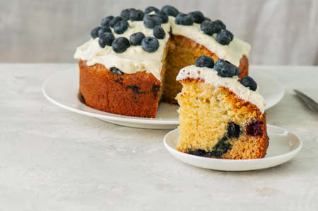 Sour cream and blueberry cake served on a plate on a white stone backgroundの写真素材