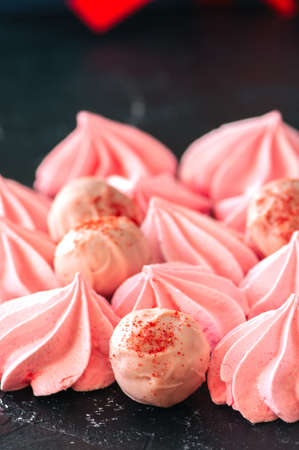 White chocolate strawberry truffles and pink meringue kisses on black stone backgroundの写真素材