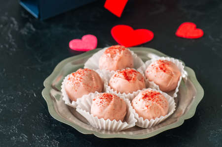 White chocolate and strawberry truffles on black stone backgroundの写真素材