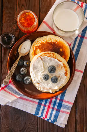 Top view of homemade pancakes in a plate, milk in a glass, jam on a wooden backdrop. Rustic style.の写真素材