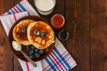 Top view of homemade pancakes in a plate, milk in a glass, jam on a wooden backdrop. Rustic style.の写真素材