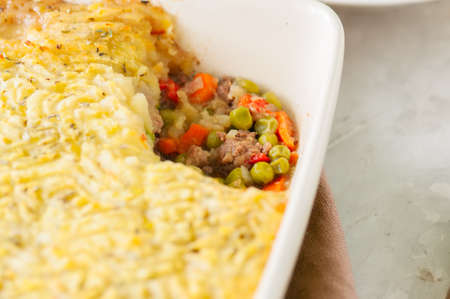 Shepherds pie -  Irish traditional food. Served in a ceramic dish on a white stone background.の写真素材