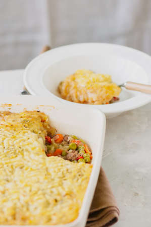 Shepherds pie -  Irish traditional food. Served in a ceramic dish on a white stone background.の写真素材