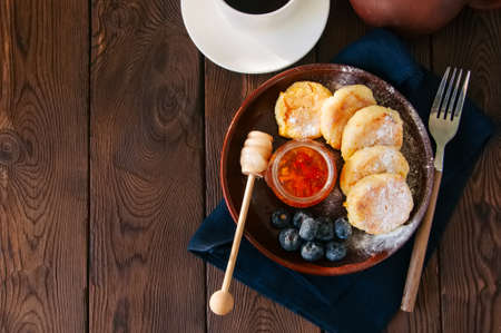 Top view of homemade cottage cheese pancakes- syrniki in a plate, jam on a wooden backdrop.の写真素材