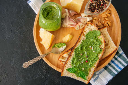 Bruschetta with basil walnut pesto sauce on a wooden plate. Black stone backdrop.の写真素材