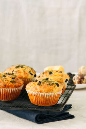 Savory muffins with olives and herbs on a wire rack on a white stone backdrop. Rustic style.の写真素材