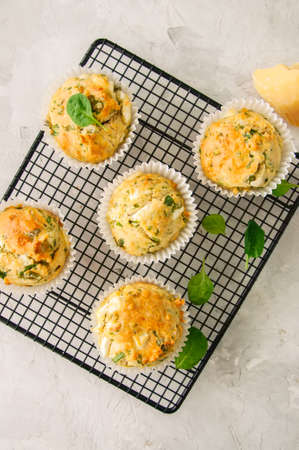 Savory muffins with feta cheese and spinach  on a wire rack on a white stone backdrop.の写真素材