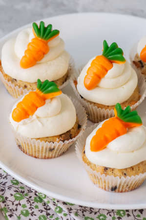 Vanilla cupcakes with chocolate chips and cream cheese frosting decorated with carrot marmalade.の写真素材