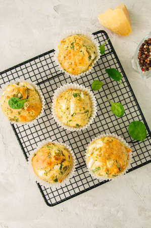 Savory muffins with feta cheese and spinach on a wooden plate on a wire rack.White stone backdrop. の写真素材