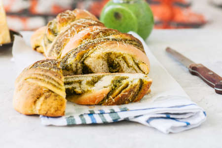 Slices of Italian pesto braided bread on a napkin, white stone background.の写真素材