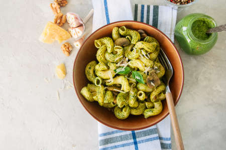 Italian pasta with basil pesto and herbs in a plate on a white stone background.の写真素材