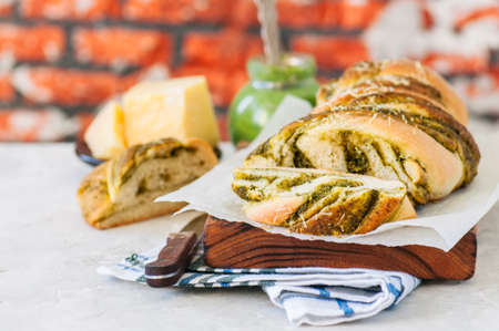 Slices of Italian pesto braided bread on a napkin, white stone background.の写真素材