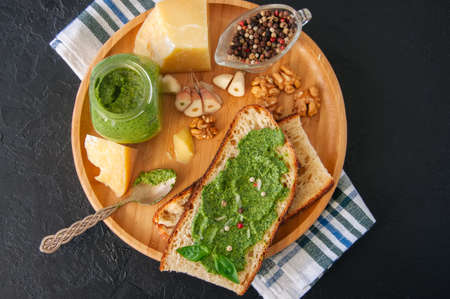 Bruschetta with basil walnut pesto sauce on a wooden plate. Black stone backdrop.の写真素材