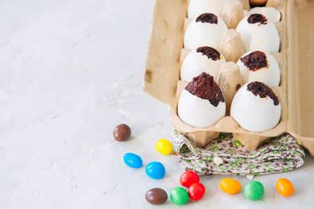 Dark chocolate brownie dessert in egg shells. Easter or funny kids party concept. White stone background.  の写真素材