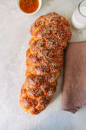 Homemade sesame seeds challah bread, glass of milk and orange jam  on a white background.の写真素材