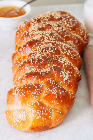 Homemade sesame seeds challah bread, glass of milk and orange jam  on a white background.の写真素材