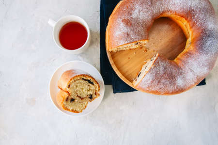 Reindling - Austrian or German festive yeasty baking for Easter. Ring cake served on a wooden plate on a white stone background.の写真素材