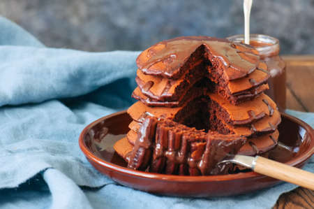 Chocolate pancakes wiyh syrup in a plate on a blue background.