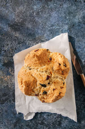 Homemadel Irish soda bread with cranberries and nuts on a baking paper on a blue stone background.の写真素材
