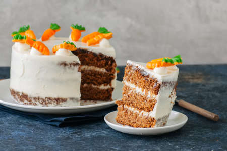 Carrot cake with cream cheese frosting decorated with carrot marmalade serving on a plate on a blue stone background.の写真素材