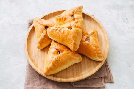 Homemade baked uchpuchmak (samsa) with meat and potato on a wooden plate on a white stone background. Overhead view and copy space.の写真素材
