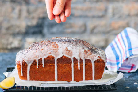 Homemade lemon poppy seed pound cake on a wire rack. Blue stone background. Close up.の写真素材