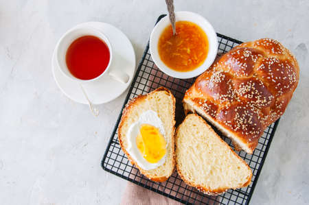 Homemade sesame seed traditional Challah bread, tea, orange jam on a white stone background. Top view.の写真素材