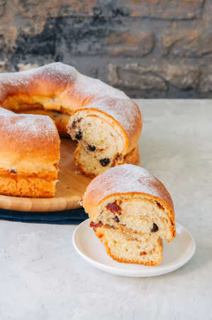 Reindling - Austrian or German festive yeasty baking for Easter. Ring cake served on a wooden plate on a white stone background.の写真素材