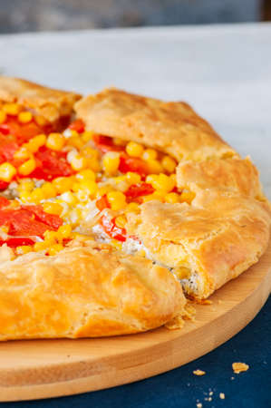 Tomato and sweet corn galette on a wooden board. Close up. White stone background.の写真素材