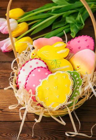 Colorful Easter bunny and egg cookies in a basket on a wooden background