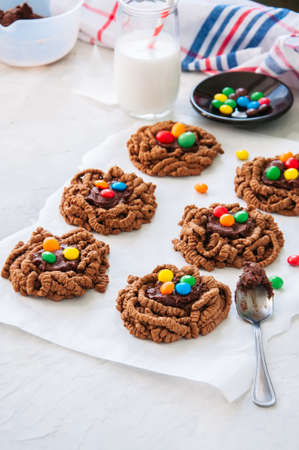 Chocolate bird's nest cookies decorated with colorful candies on a white background. の写真素材