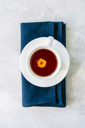 A cup of flower tea on a blue napkin on a white stone background. Top view and copy space.の写真素材