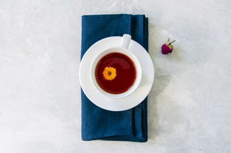 A cup of flower tea on a blue napkin on a white stone background. Top view and copy space.の写真素材